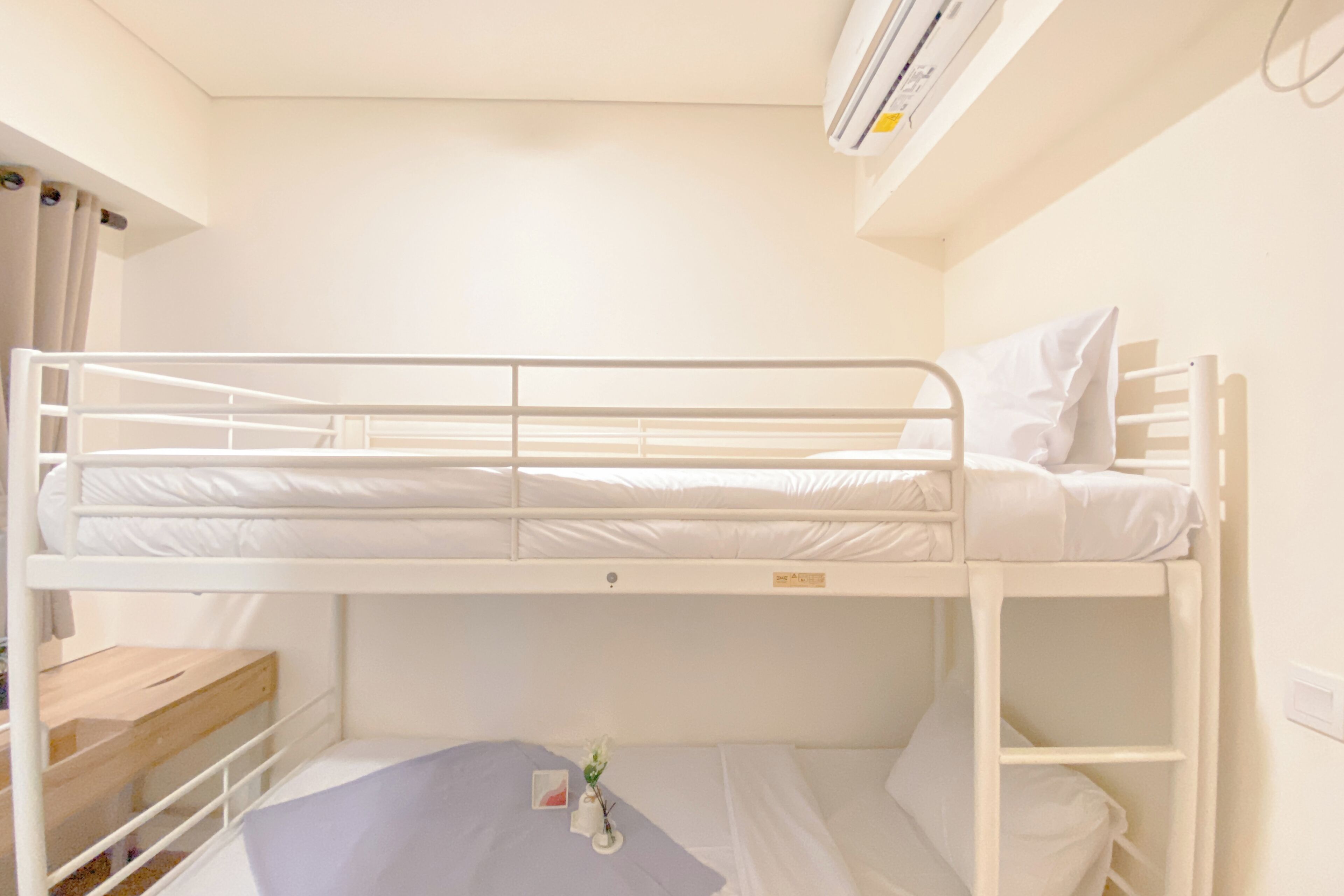 Een slaapkamer met een stapelbed, een houten bankje en een kleine tafel.