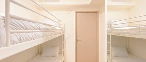 A room with two bunk beds, a door, and an air conditioning unit.