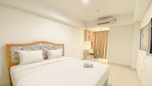 A hotel room with a large bed, a desk, a chair, and an air conditioning unit. - Good And Homey Studio At The Pinnacle Apartment (Semarang)