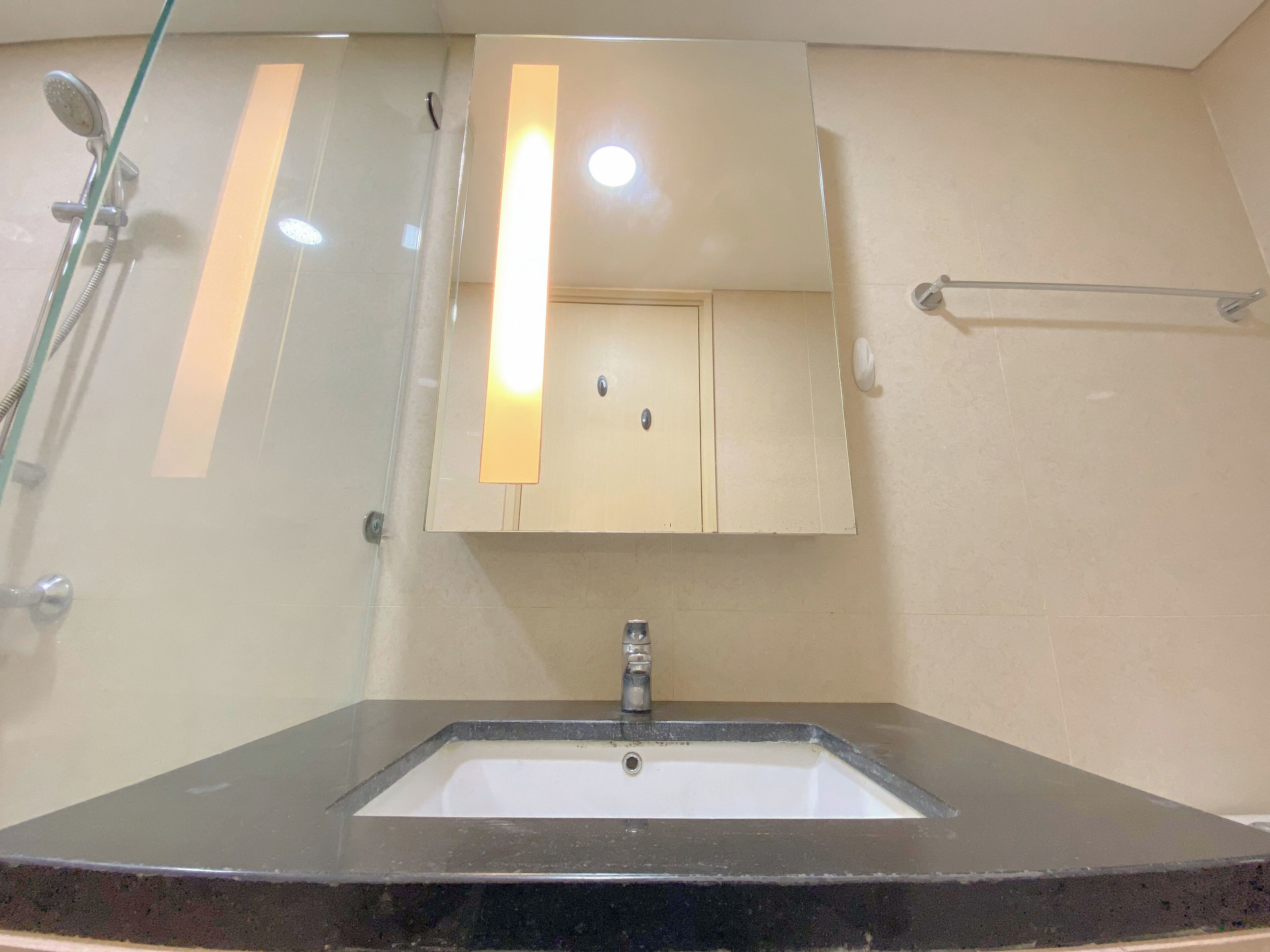 A bathroom with a sink, mirror, and shower.