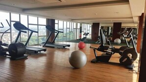 A gym with treadmills, weight machines, and exercise balls. - Good And Homey Studio At The Pinnacle Apartment (Semarang)