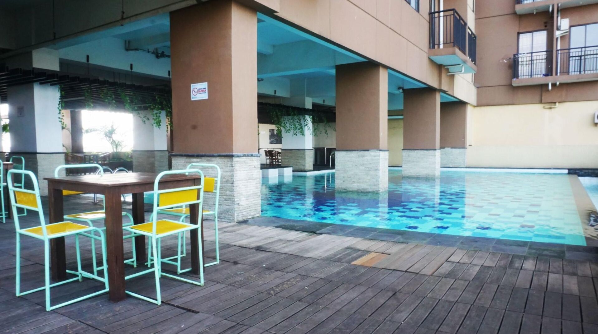Area piscina esterna con solarium in legno, sedie e tavolo in metallo.