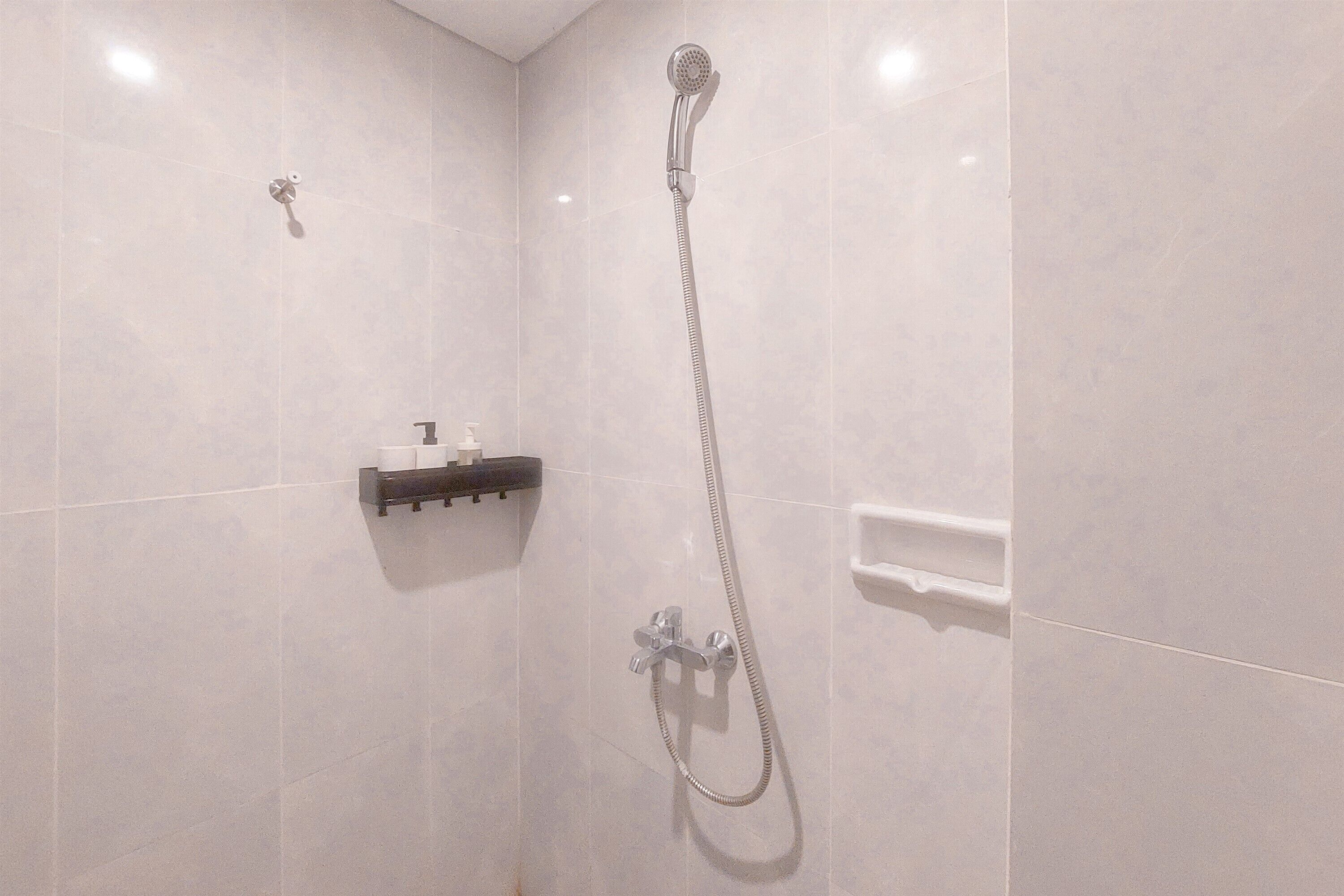 Un baño moderno con ducha, dispensador de jabón y barra para toallas.