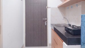 A modern kitchen with a dark wood door, a black countertop, and a sink. - Good Choice And Modern Studio Apartment At Serpong Garden (Cisauk)
