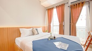 Een hotelkamer met een bed, een raam met gordijnen en uitzicht op buiten.