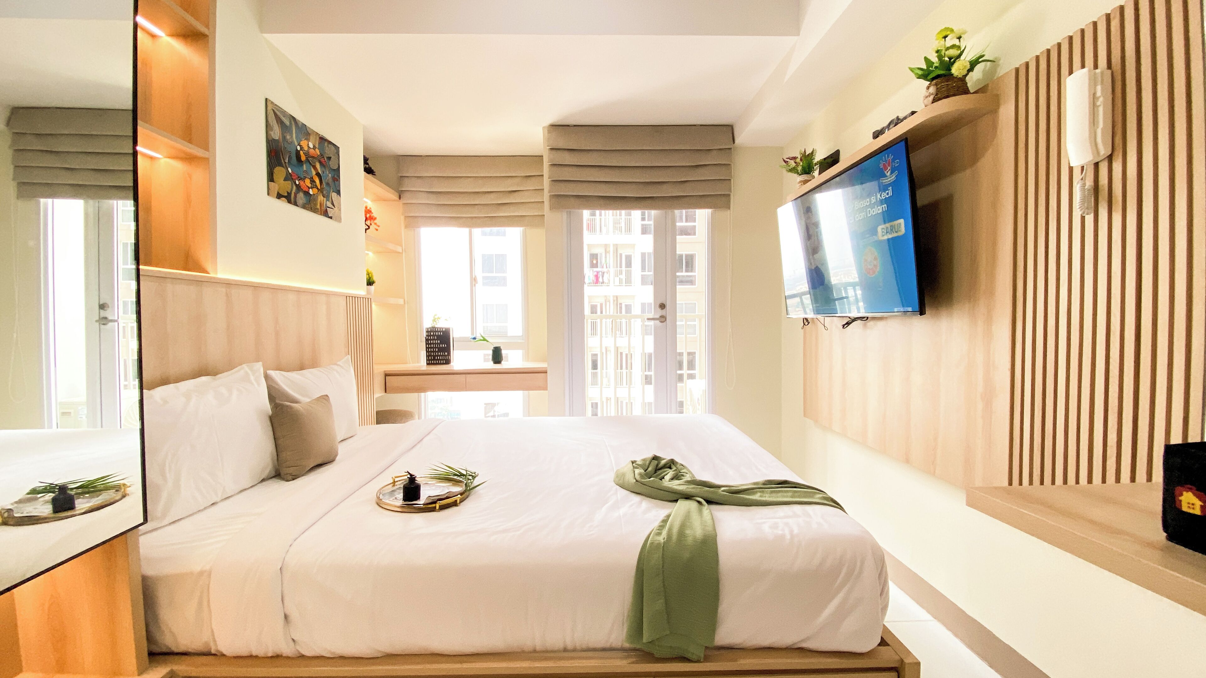 Een moderne hotelkamer met een groot bed, een flatscreen televisie aan de muur en een raam met uitzicht op de stad.