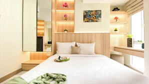 A modern hotel room with a large bed, a bedside table, a mirror, and a window with a view. - Brand New Studio Room At Tokyo Riverside Pik 2 Apartment (Teluknaga)