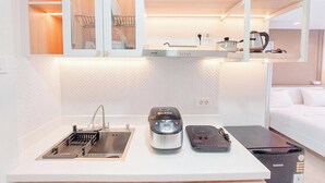 A compact kitchenette with a sink, a rice cooker, and a portable stove. - Comfortable Studio At Podomoro City Deli Medan Apartment (Medan)