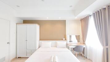 A hotel room with a large bed, a desk, a wardrobe, and a window with curtains.