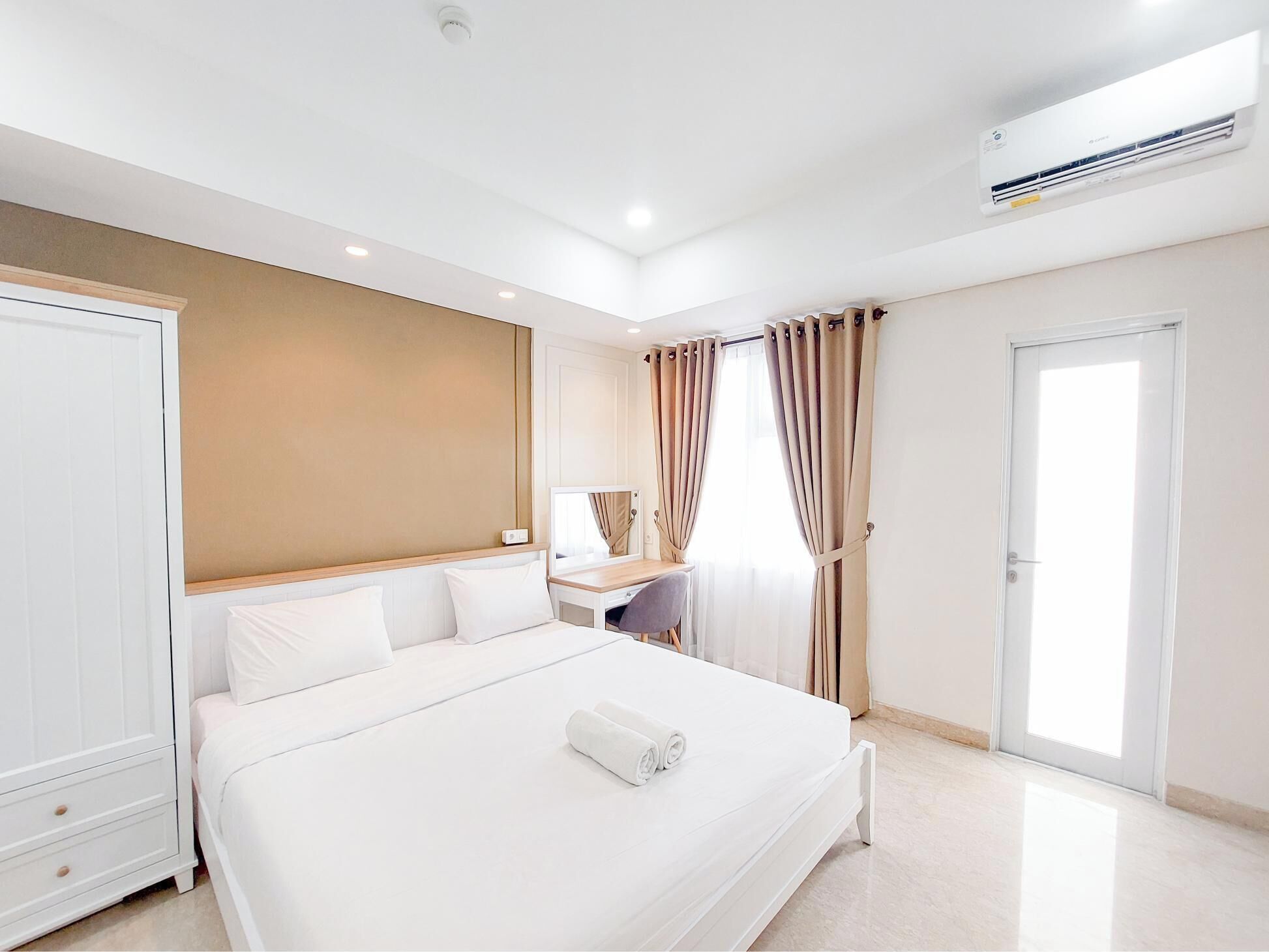 A modern hotel room with a large bed, a desk, and an air conditioning unit.