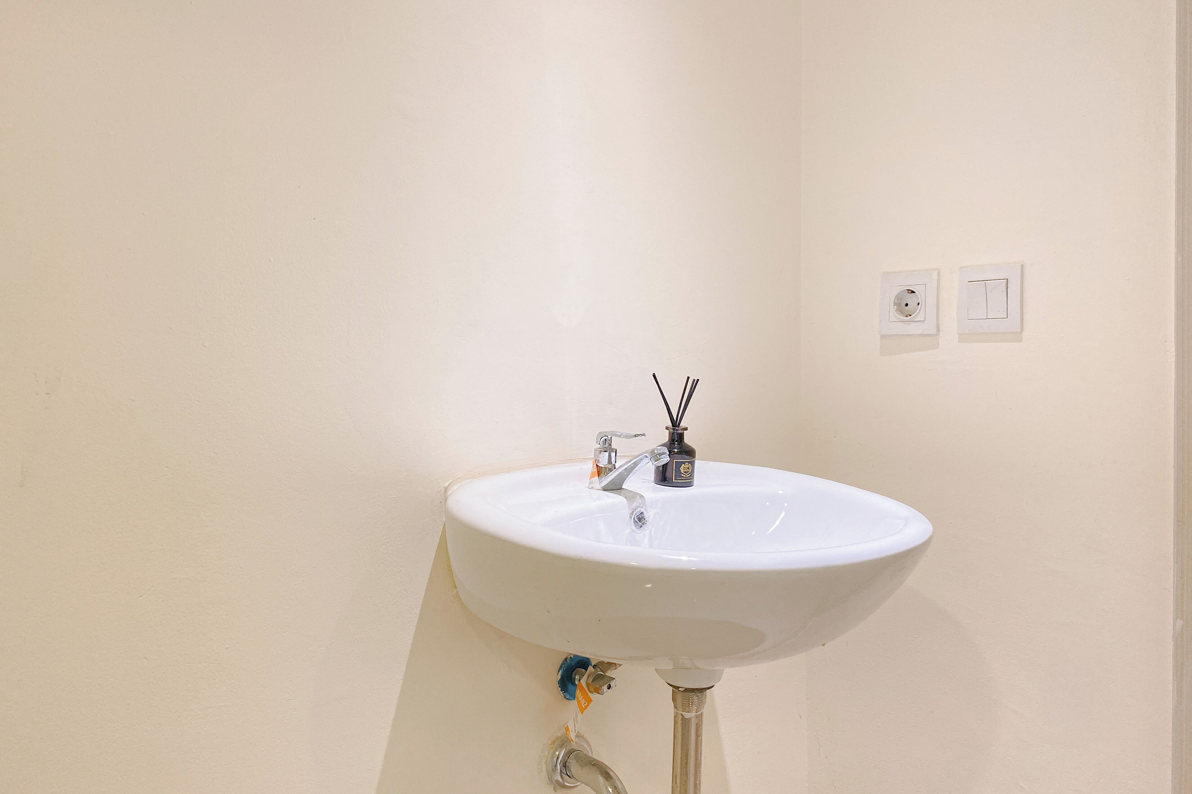 Ein weißes Waschbecken mit einem Wasserhahn, einer Seifenspender und zwei an der Wand montierten Lichtschaltern.