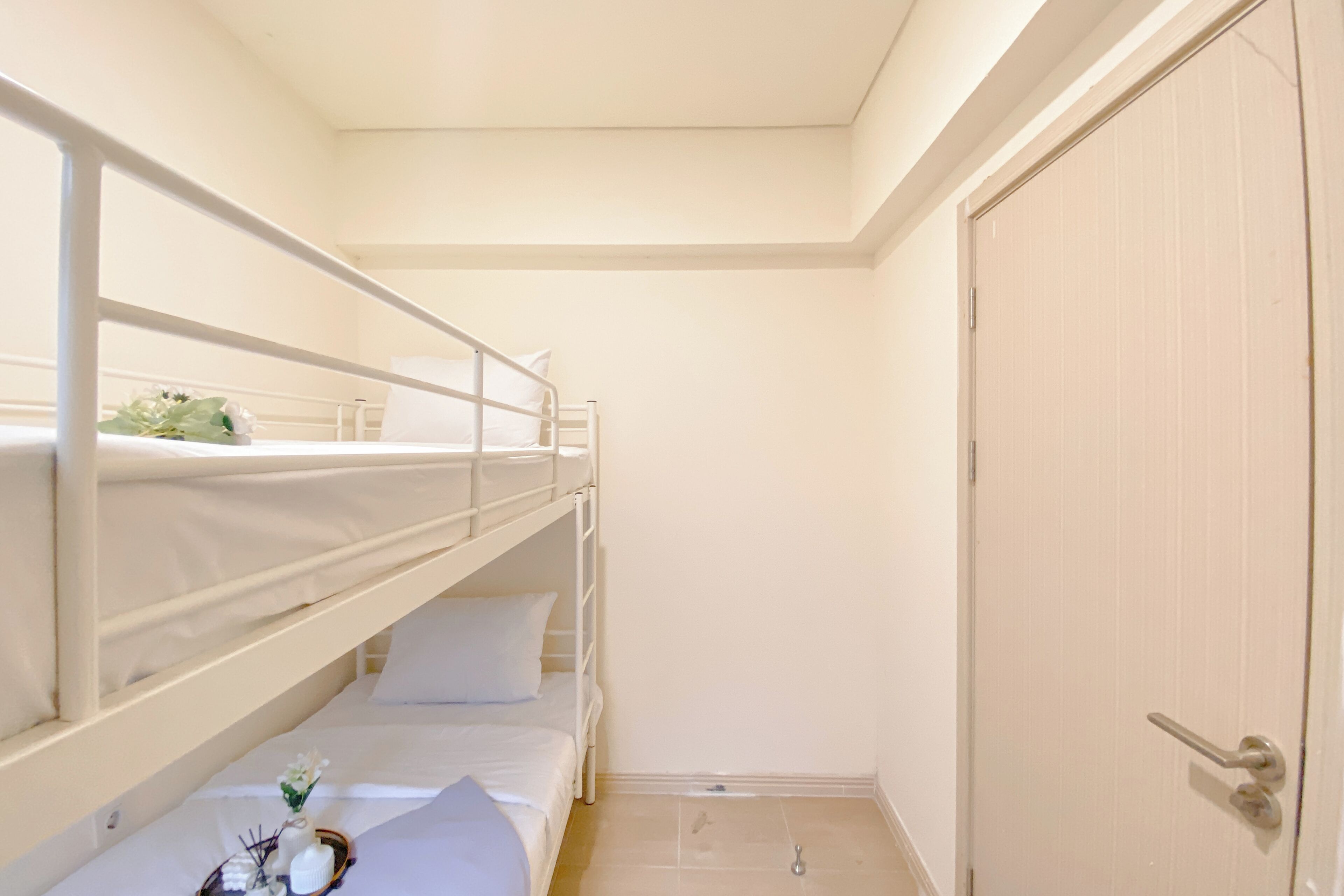 A bunk bed room with a door and a small table with a vase of flowers.