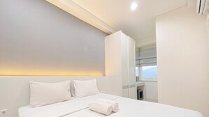 Una moderna camera d'hotel con un letto grande, lenzuola bianche, un comodino e vista sulla città attraverso una finestra.