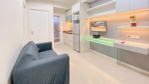 Una cucina moderna con TV integrata, un piano di lavoro in vetro e una piccola pianta sullo scaffale.