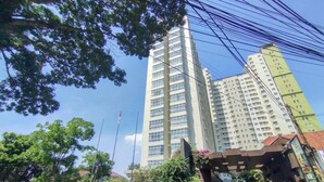Un edificio moderno e alto, su più piani, circondato da alberi e altri edifici.