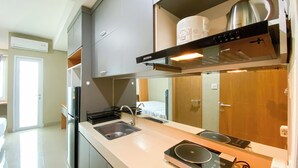 A modern kitchen with a built-in oven, a sink, and a stove. - Warm And Cozy Living Studio Apartment At B Residence (Pagedangan)