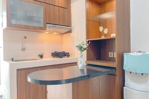Una cocina moderna con armarios de madera, encimera negra, estufa integrada y dispensador de agua.