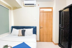 A hotel room with a bed, a wooden door, and an air conditioning unit. - Good And Homey 2Br At Apartment Green Palm Residence (Jakarta)