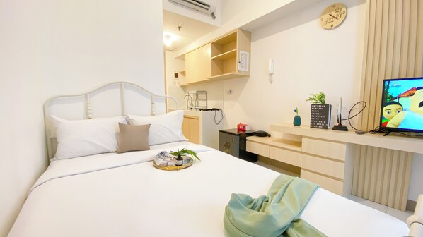 Cozy retreat with a neatly made bed, compact kitchenette, and a flat-screen TV.