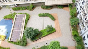 An aerial view of a courtyard with a swimming pool, green landscaping, and a few people. - Good And Cozy Studio Apartment At Tokyo Riverside Pik 2 (Teluknaga)