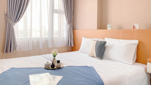 A neatly made bed with white and gray bedding, a blue throw blanket, and a tray with a vase and candles. - Best Choice And Homey 1Br Apartment Royal Olive Residence (Jakarta)