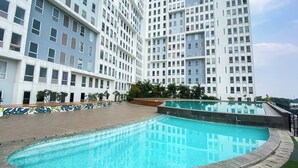 Un bâtiment moderne doté d’un espace piscine, comprenant une piscine aux lignes courbes et une allée dallée.