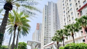 A high-rise building with multiple floors, surrounded by palm trees and other greenery. - Homey And Comfort 2Br Green Bay Condominium Apartment (Jakarta)