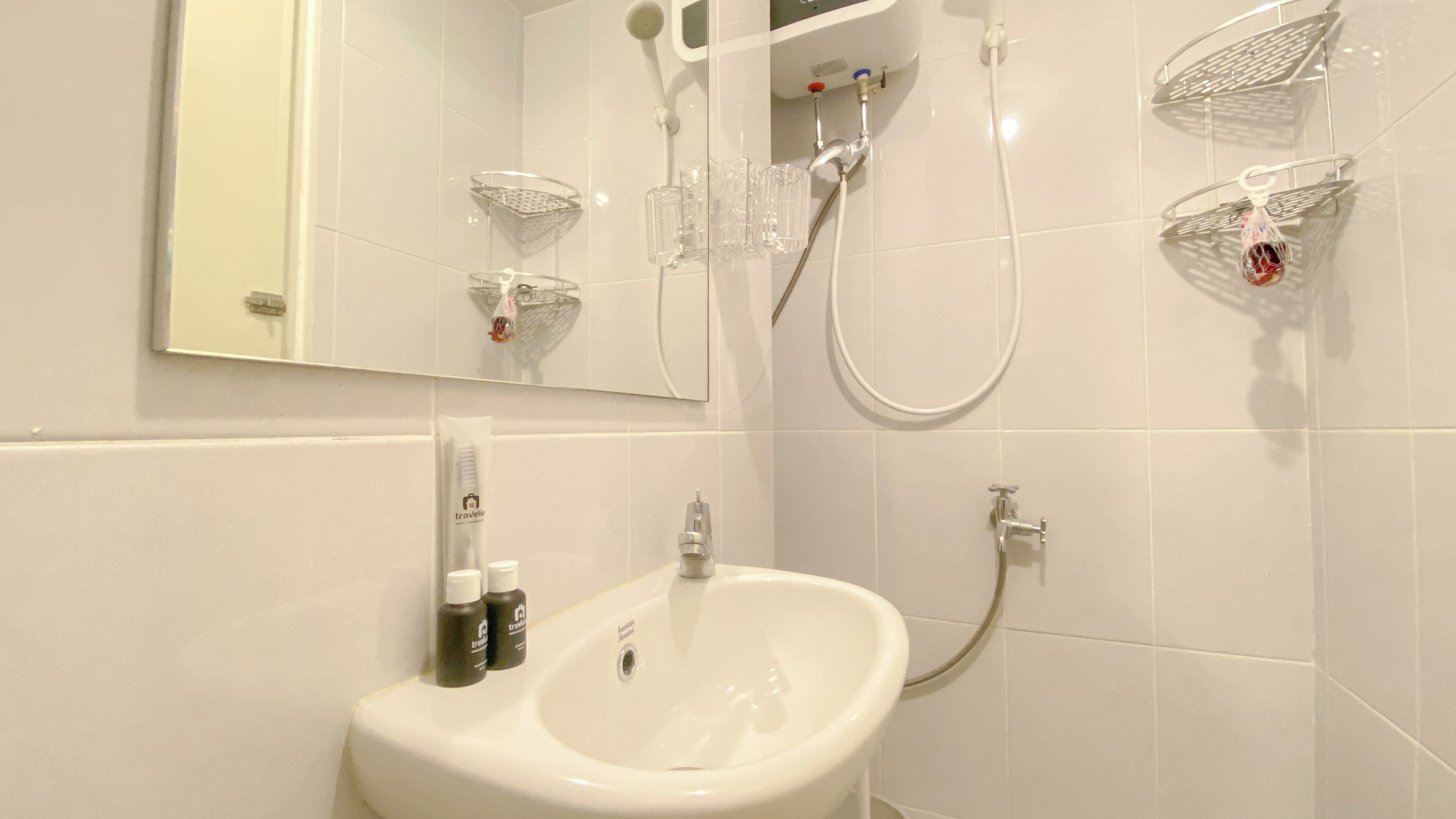 A modern bathroom with a white sink, a mirror, and a shower with a handheld showerhead.