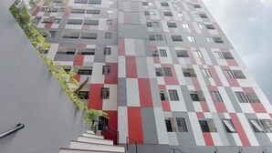 Un edificio de varios pisos con una fachada geométrica, que presenta una combinación de paneles rojos, grises y blancos.