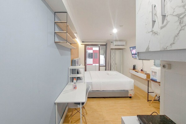 Une chambre d’hôtel de taille réduite, comprenant un lit, un bureau, une chaise, une télévision et un distributeur d’eau.