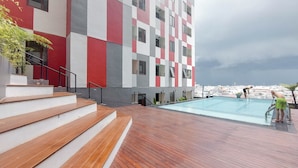 Un edificio moderno con fachada a cuadros, una terraza de madera y una piscina.