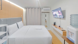 Habitación de hotel con cama, televisión, dispensador de agua y pared de paneles de madera.