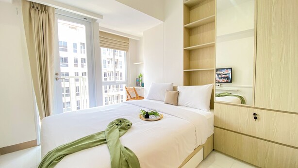 Une chambre d’hôtel avec un lit, une télévision, une armoire en bois et une fenêtre avec des rideaux.