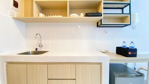 Une cuisine moderne dotée d’un évier en acier inoxydable, de meubles en bois et d’un plan de travail sur lequel se trouve une boîte noire contenant des bouteilles d’eau.