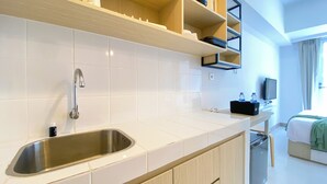 Une cuisine moderne dotée d’un évier en acier inoxydable, de carreaux blancs, de meubles en bois et d’une étagère intégrée au-dessus du plan de travail.