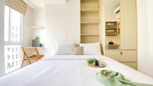 Une chambre d’hôtel comprenant un lit, un bureau, une chaise et une étagère.