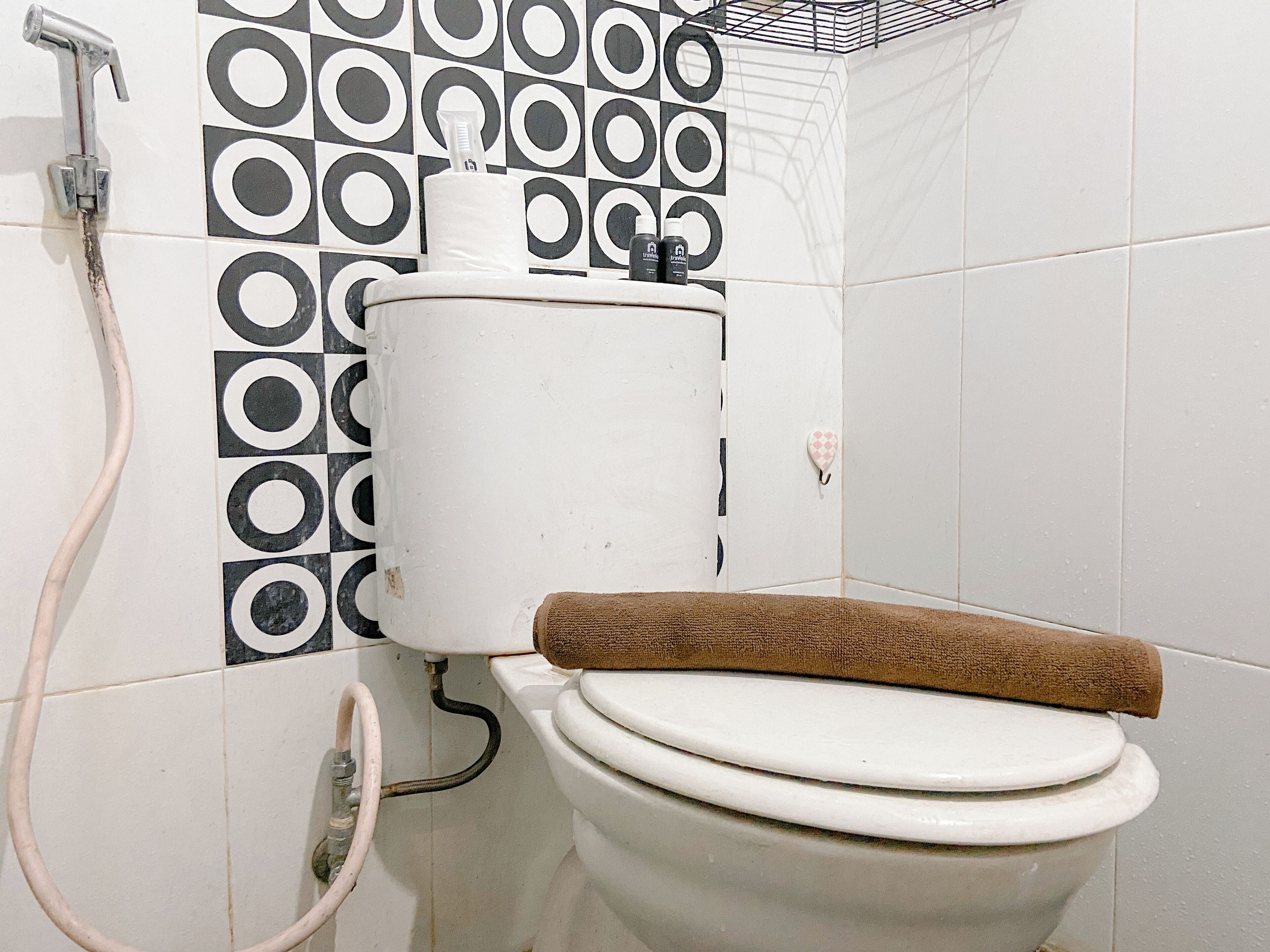 A bathroom with a toilet, a shower, and a patterned wall.