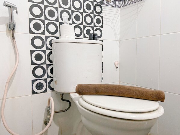 A bathroom with a toilet, a shower, and a patterned wall.