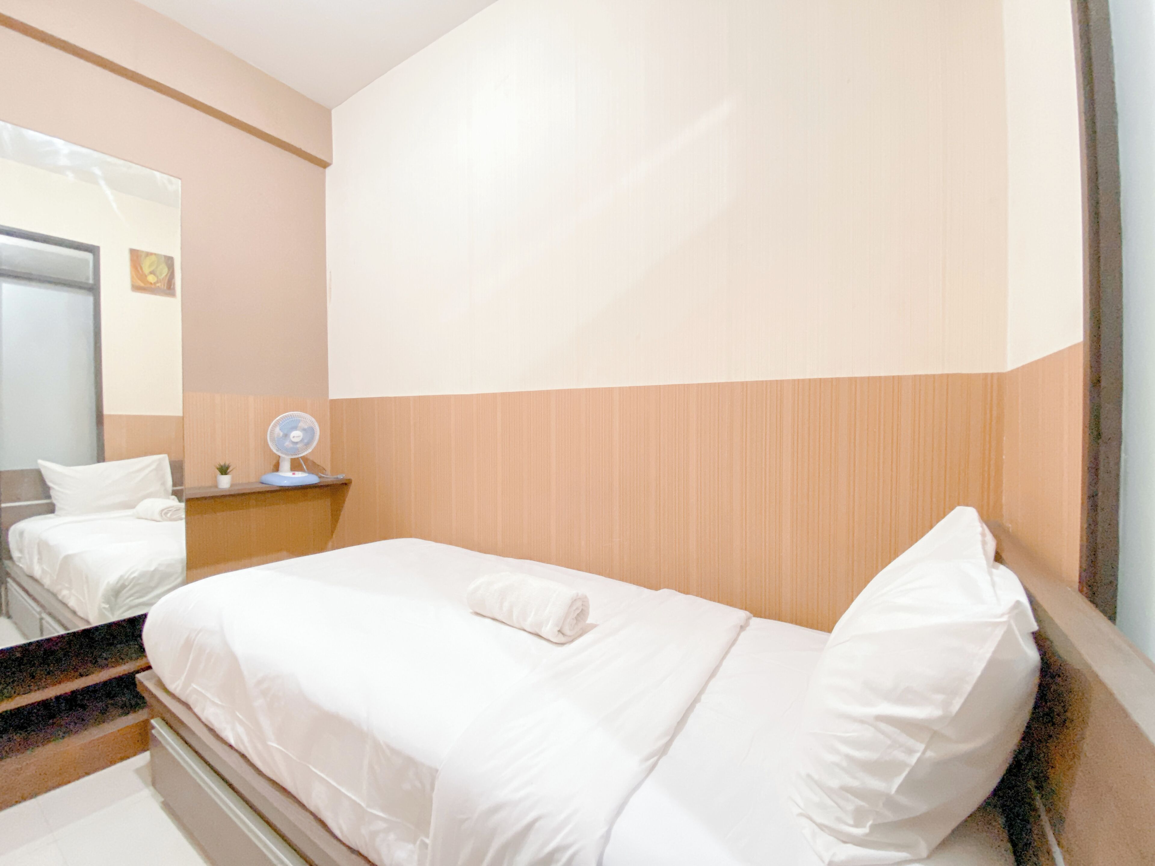 Una habitación de hotel con cama, mesita de noche con lámpara y espejo.