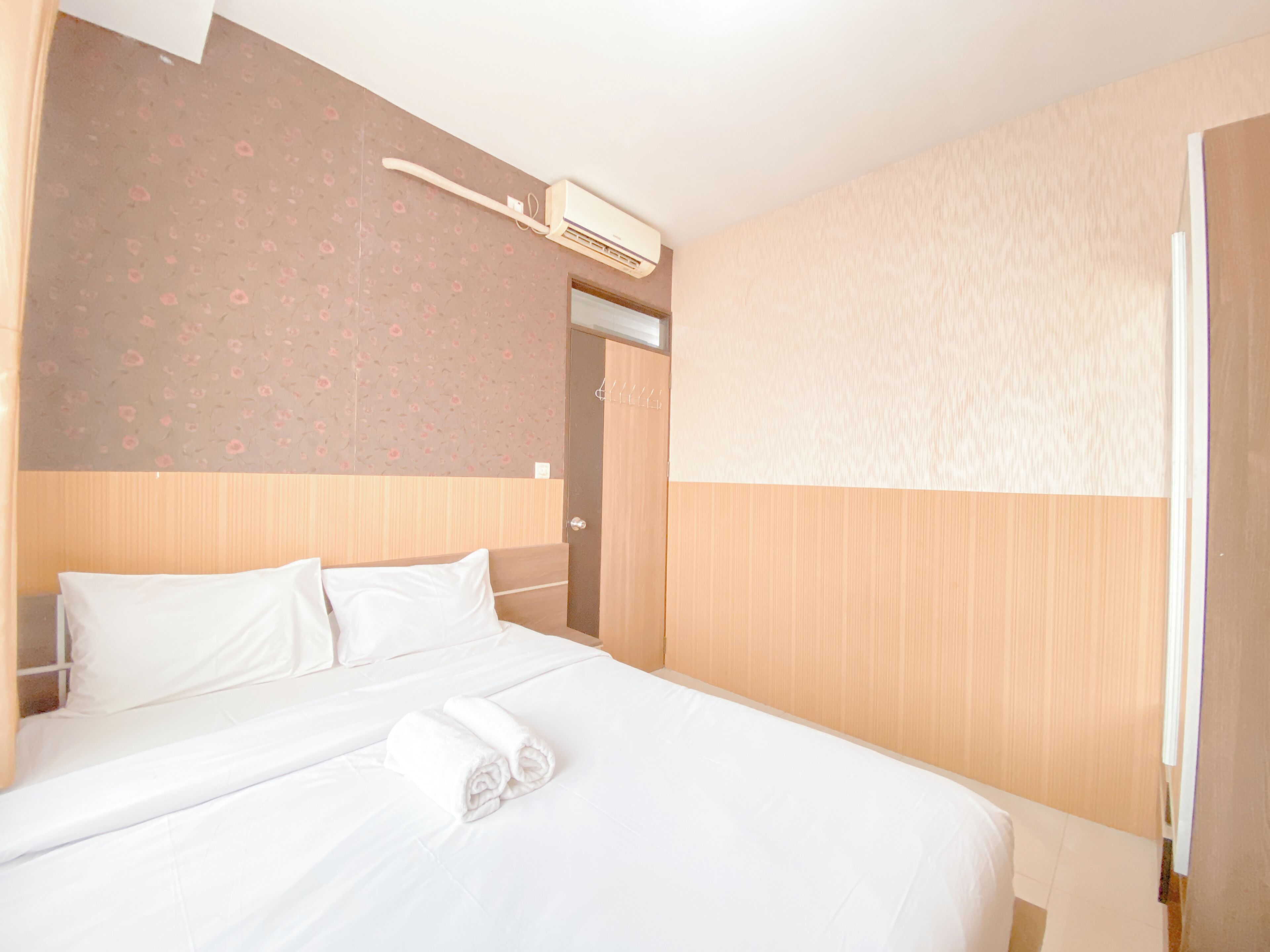 A hotel room with a bed, a wall-mounted air conditioner, and a door.