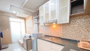 A modern kitchen with white cabinets, a black countertop, and a tiled backsplash. - Scenic 2Br At The Edge Bandung Apartment (Cimahi)