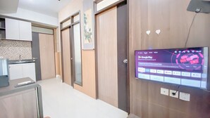A modern hotel room with a flat-screen TV displaying Google Play, a kitchenette, and a wooden door. - Scenic 2Br At The Edge Bandung Apartment (Cimahi)