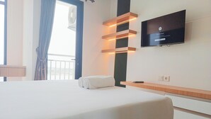 Une chambre d’hôtel avec un grand lit, un téléviseur à écran plat fixé au mur et une fenêtre avec des rideaux.