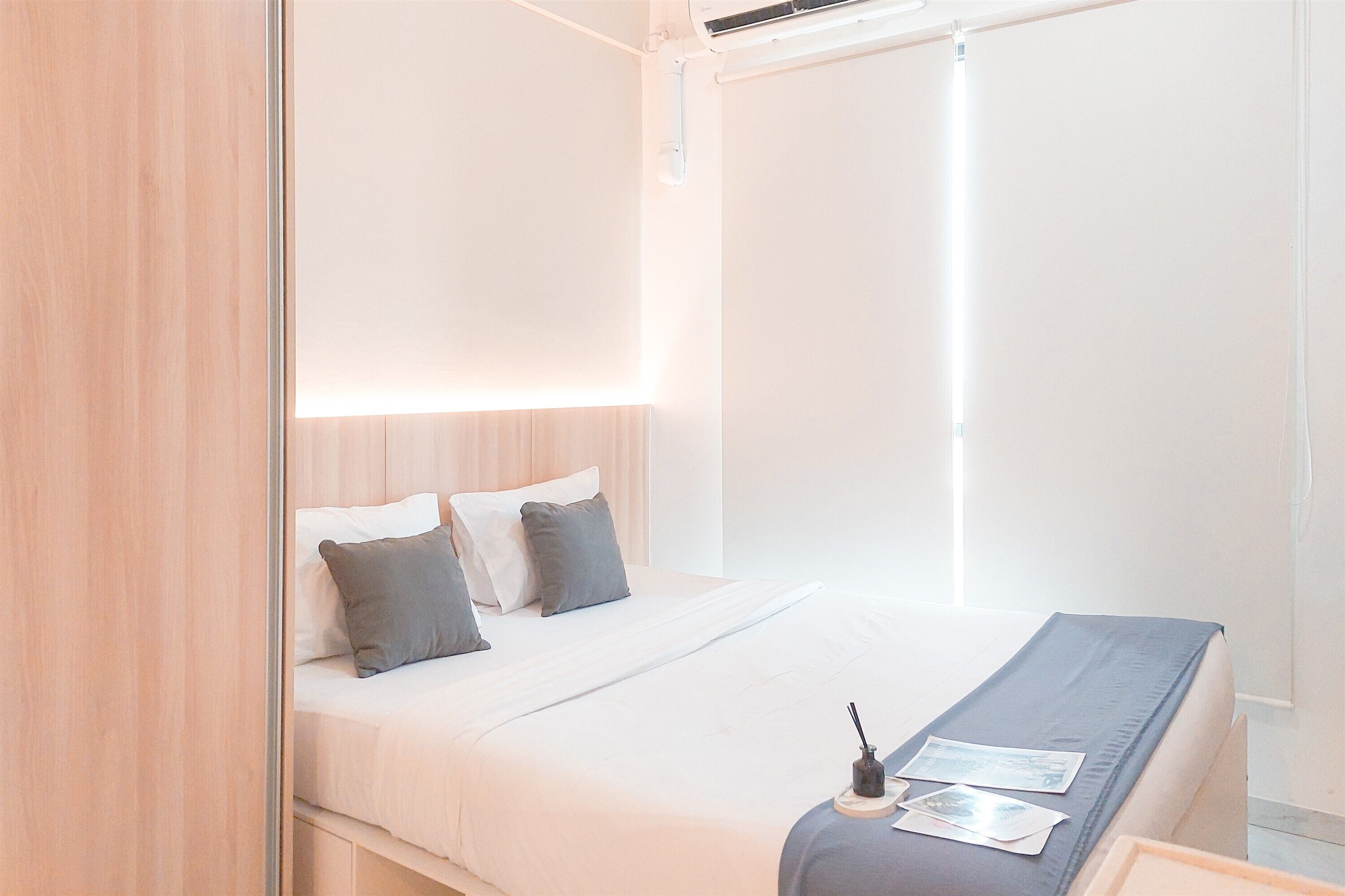A modern bedroom with a bed, bedside table, and a window with blinds.