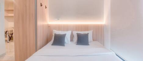 A hotel room with a bed, two pillows, a wooden headboard, and a sliding door.