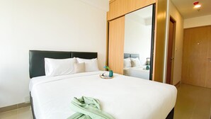 Une chambre d’hôtel avec un grand lit, une armoire en bois et un miroir.