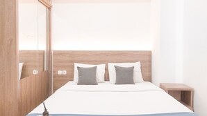 A hotel room with a wooden headboard, two pillows, a bedside table, and a magazine on the bed.