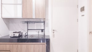 A kitchen with a black countertop, a stove, and wooden cabinets.
