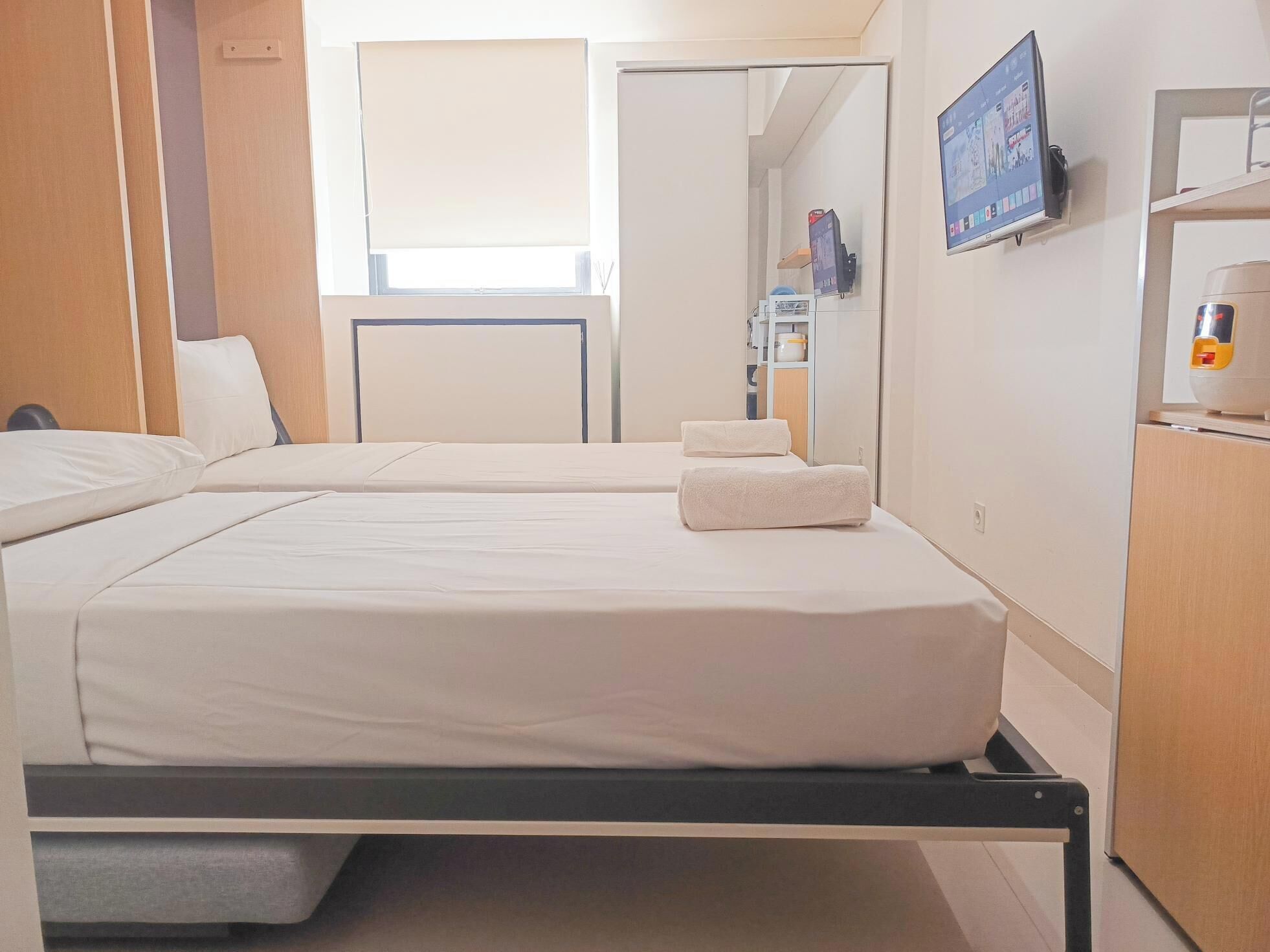 Habitación de hotel con dos camas, un televisor en la pared y un escritorio con una lámpara.