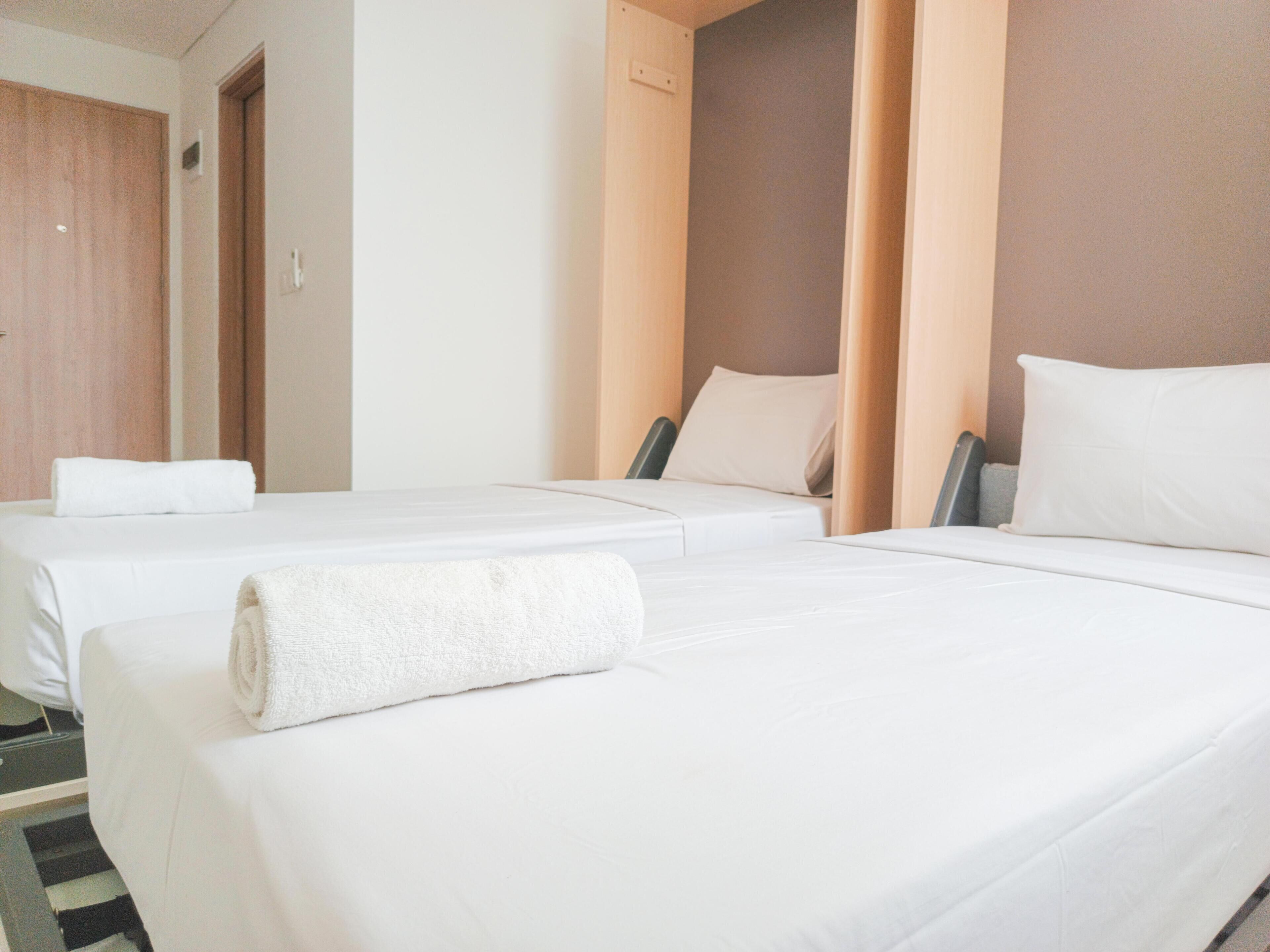 A hotel room with two beds, a wooden door, and a plain wall.